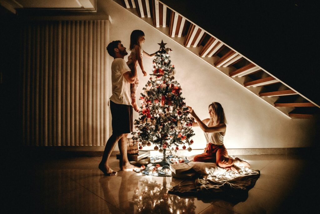 クリスマスツリーに飾り付けをしている家族
